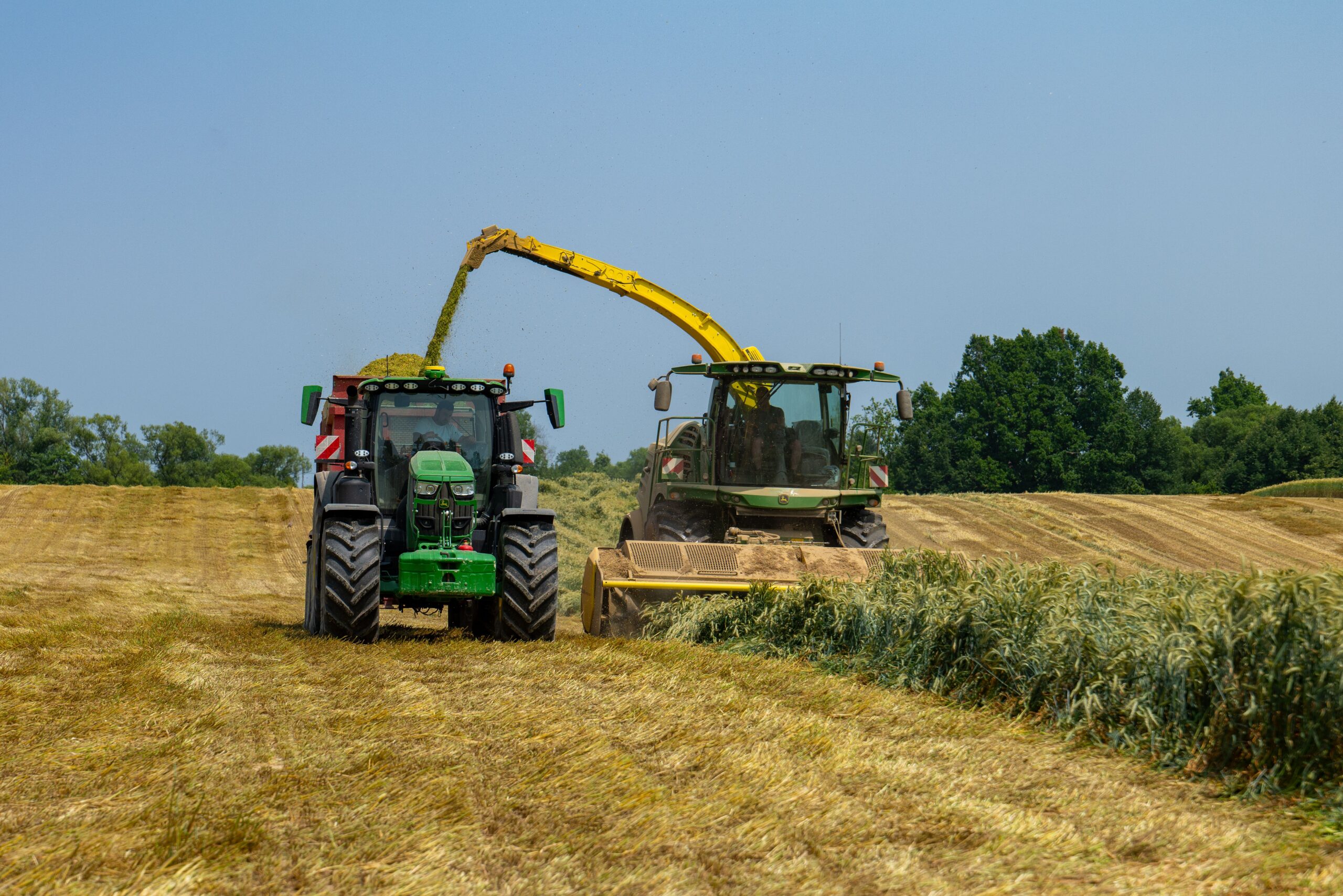 Two tractors working in a field in Garešnica, Croatia, during a sunny summer day.